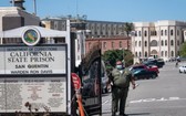 一名加州懲戒及改造局(CDCR)的官員戴著口罩站在聖昆廷州立監獄的前門。(圖源:Getty Images)
