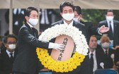 日本首相安倍晉三(中)9日在長崎市原爆75周年紀念儀式獻上花圈。(圖源:AFP)