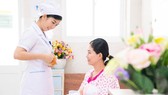 Nữ hộ sinh tư vấn cho sản phụ về tư thế cho con bú.