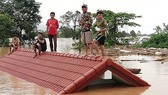 Người dân đứng trên nóc nhà chờ giải cứu khi nước lũ dâng cao do vỡ đập
