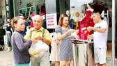 Một phụ nữ nghèo (bìa trái) nhận suất ăn sáng cho cả nhà từ nhóm bạn anh Huỳnh Nghĩa