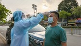 Kiểm tra thân nhiệt cho tài xế lái xe vào TPHCM. Ảnh: HOÀNG HÙNG