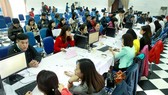 Tax officials (on the right side of the tables) receive personal income tax finalisation documents from Hanoi residents. The Vietnamese Government aims to considerably increase the number of administrative procedures processed via electronic systems in th