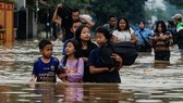 Residents walking along a flooded road as they evacuate Dayeuhkolot village in Bandung. (Photo: AFP)