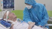 Phi công người Anh đã tỉnh, bắt tay nhân viên chăm sóc y tế. Ảnh cắt từ clip của Bệnh viện Chợ Rẫy