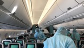 Tiếp viên mặc đồ bảo hộ phục vụ hành khách trên máy bay