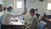 Đo thân nhiệt thuyền viên trước khi đưa lên bờ cách ly