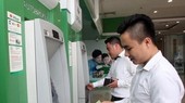 Office workers withdraw money from an ATM. (Photo: VNA)