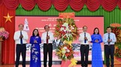 HCMC's leaders (L) presents flowers to Cu Chi District's leaders (R) celebrating 55 years of receiving the title “Iron Land and Bronze Citadel” .