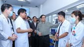 Prime Minister Pham Minh (center) talks with doctors at the Bach Mai Hospital in Hanoi. (Photo: SGGP)