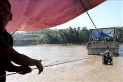 Người dân tìm cách qua sông bằng hệ thống dây kéo khi cây cầu bị phá huỷ do mưa lũ tại tỉnh Aceh, Indonesia ngày 1-12. Ảnh: THX/TTXVN