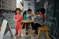 Trẻ em vui chơi bên ngoài một quán cà phê ở Bắc Kinh, Trung Quốc. Ảnh: TTXVN