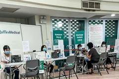 Một phụ nữ Singapore được tư vấn về những tác dụng phụ sau khi chích mũi vaccine thứ 3 trước khi lấy giấy chứng nhận, tại một trung tâm tiêm chủng cộng đồng do Tập đoàn Y tế Raffles Medical điều hành theo ủy nhiệm của chính phủ. 
