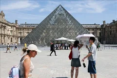 Du khách che ô chống nắng khi tham quan viện bảo tàng Louvre ở Paris, Pháp ngày 25-6. Ảnh: THX/TTXVN