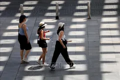 Người dân di chuyển trên đường phố dưới trời nắng nóng tại Seville, Tây Ban Nha. Ảnh: THX/TTXVN