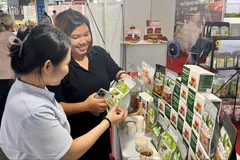 Người tiêu dùng chọn mua mứt đặc sản như mãng cầu, dừa non... tại một gian hàng ở Nhà thi đấu Phú Thọ, chiều 23-10. Ảnh: GIA HÂN