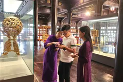 Du khách tham quan, tìm hiểu cổ vật trưng bày tại Bảo tàng cổ vật cung đình Huế có gắn chip NFC. 