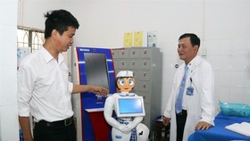 Vo Hong Quan, director of the Centre of Information and Technology under the Eastern People Military Hospital in HCM City (left), introduces the nurse robot named Tam (Photo:VNA)