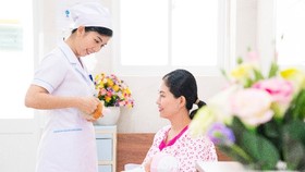 Nữ hộ sinh tư vấn cho sản phụ về tư thế cho con bú.