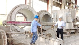 Kỹ sư Trần Quốc Toản (phải) hướng dẫn công nhân ứng dụng những cải tiến mới vào vận hành sản xuất