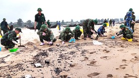 Lực lượng chức năng thu gom cặn dầu loang trên bờ biển xã Kỳ Lợi, Hà Tĩnh