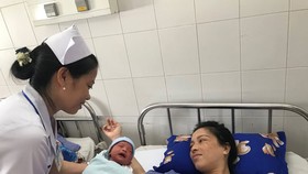 Bác sĩ chăm sóc cho mẹ con sản phụ, sau khi phẫu thuật thành công
