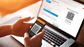 A customer makes payment by QR code for his order online. (Photo: VNA)