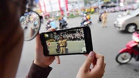A citizen films a on-duty traffic police in HCM City. — Photo luatvietnam.vn