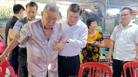 Chairman Phong leads resident Hai by the hand (Photo: SGGP)