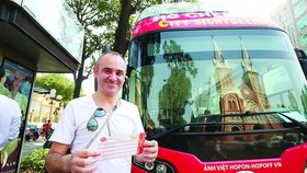 A foreign tourist buys a fare for hop-on hop-off tour in HCMC (Photo: SGGP)