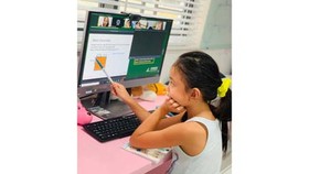 Second grader Pham Bao Thien Kim is taking part in an online lesson at home. (Phot: SGGP)