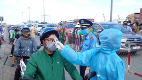 A driver has his body temperature taken before entering Ho Chi Minh City (Photo: SGGP)