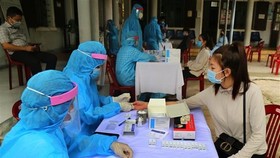Medical workers conduct quick tests for people returning from COVID-19-hit regions (Photo: VNA)