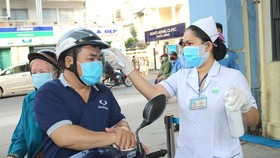 Relatives of patients are measured temperature before entering a hospital in HCMC (Photo: SGGP)