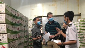 Staffs of the Vietnamese Plant Protection Department and US experts check shipments of Vietnamese fresh fruits