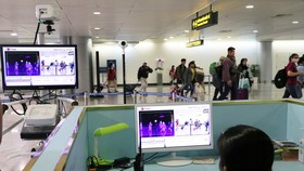 Nhân viên sân bay đo tầm nhiệt kiểm tra sàng lọc người nhiễm Covid-19. Ảnh: HOÀNG HÙNG