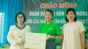 Bà Lý Việt Trung, Phó Tổng Biên tập Báo SGGP (bên phải) cùng đại diện Công ty TNHH Grab trao hỗ trợ 100 triệu đồng cho bà Nguyễn Thị Thu Hà, Giám đốc Trung tâm Võ Hồng Sơn. Ảnh: NGUYỄN TRANG