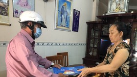 Cán bộ tại Quận 10 (TPHCM) phát tờ rơi tuyên truyền đến từng hộ dân trong địa bàn quận. Ảnh: KIM HUYỀN