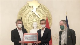 Chủ tịch Đảng Cộng sản Đức Patrik Köbele (trái) và ông Stefan Kühner (phải) trao số tiền quyên góp cho Đại sứ Nguyễn Minh Vũ. Ảnh: TTXVN
