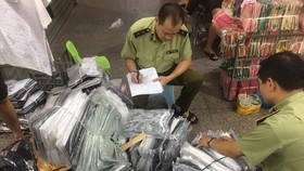 Cán bộ QLTT kiểm kê các lô hàng thời trang nhái, lậu trong chợ Ninh Hiệp hôm 4-6