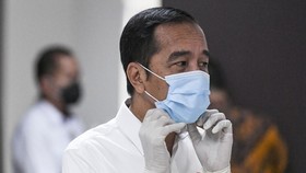 President Joko Widodo adjusts his face mask while visiting COVID-19 patients (Photo: AFP)