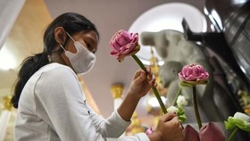 A young student is placing flowers at an altar in a Buddhist pagoda in Phnom Penh. (Photo: AFP)