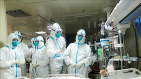 Nhóm bác sĩ bệnh viện Trường đại học quân y số 2 kiểm tra sức khỏe một bệnh nhân tại bệnh viện Hankou ở Vũ Hán, tỉnh Hồ Bắc ngày 27-1. Ảnh: THX/TTXVN