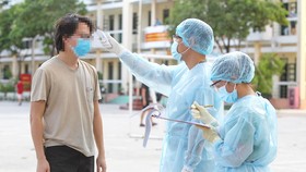 Đo thân nhiệt cho người nghi ngờ mắc bệnh trong khu cách ly tại Trường Quân sự Quân khu 7, TPHCM. Ảnh: HOÀNG HÙNG