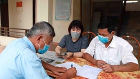 Chi trả tiền hỗ trợ cho người dân gặp khó khăn do COVID-19. Ảnh: TTXVN