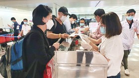Khách từ Hàn Quốc thực hiện tờ khai y tế tại sân bay Tân Sơn Nhất rạng sáng 24-2. Ảnh: THÀNH SƠN