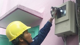 Nhân viên ngành điện kiểm tra việc lắp đặt công tơ đo đếm từ xa mới tại nhà dân