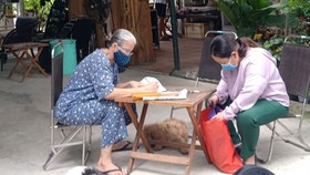 Công chức Nguyễn Thị Thu Hằng (phải) thuộc UBND phường Linh Trung (quận Thủ Đức) nhận hồ sơ hành chính và trả kết quả tại nhà người dân. Ảnh: KIỀU PHONG