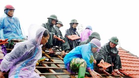 Lực lượng chức năng giúp người dân ở xã Thịnh Lộc (huyện Lộc Hà, tỉnh Hà Tĩnh) lợp lại mái nhà sau mưa bão. Ảnh: DƯƠNG QUANG