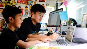 Em Nguyễn Huỳnh Thông, lớp 3 trường Võ Thị Sáu đang làm quen với cách học trực tuyến với sự hướng dẫn của người anh Nguyễn Huỳnh Bách, lớp 7 trường Đinh Thiện Lý. Ảnh: THANH TÙNG